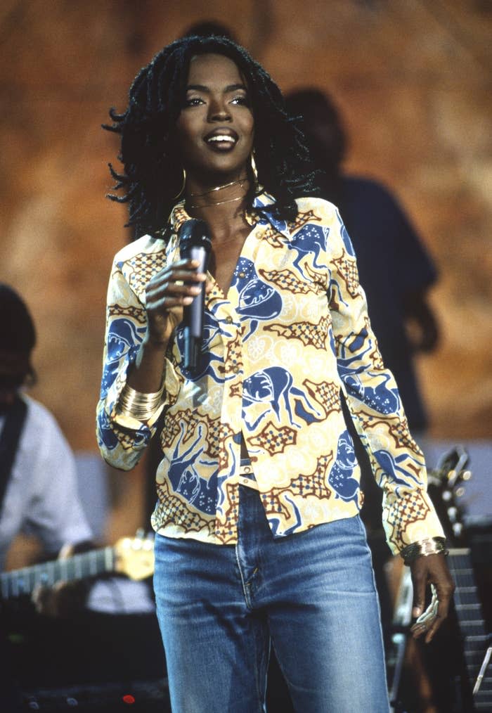 Lauryn Hill performs on stage with a microphone on her hand.