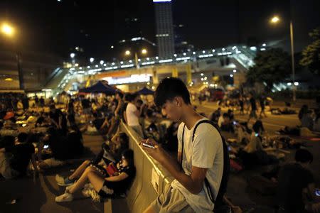 A protester looks at his mobile phone screen as he joins others to block areas around the government headquarters in Hong Kong October 5, 2014. REUTERS/Carlos Barria