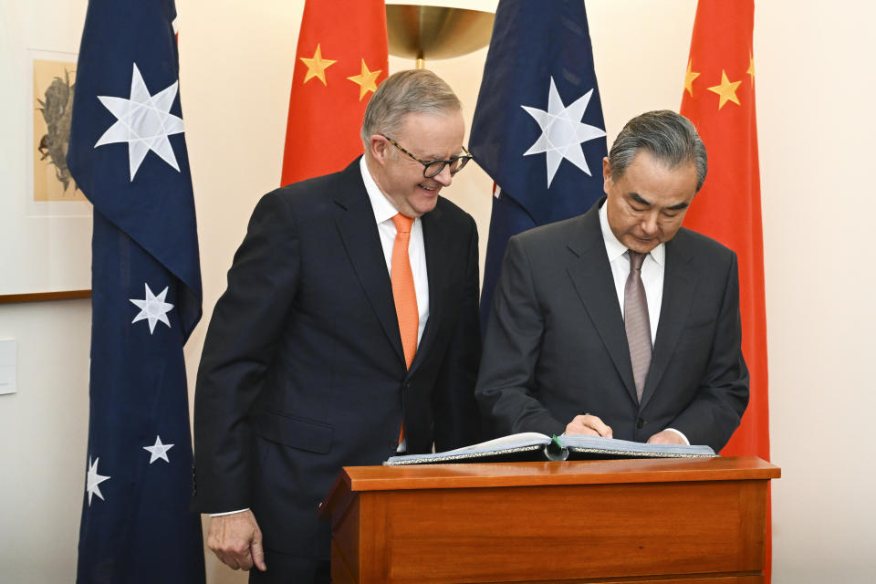 Australian Prime Minister Anthony Albanese, left, looks on as Chinese Foreign Minister Wang Yi signs the visitors book during a meeting at Parliament House in Canberra, Australia, Wednesday, March 20, 2024. Wang is on a high-ranking diplomatic tour of Australia and New Zealand this week. (Lukas Coch/AAP Image via AP)