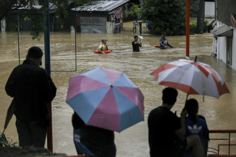 People watch another walk along a flooded road due to Typhoon Vamco in Marikina, Philippines, Thursday. Nov. 12, 2020. The typhoon swelled rivers and flooded low-lying areas as it passed over the storm-battered northeast Philippines, where rescuers were deployed early Thursday to help people flee the rising waters. (AP Photo/Basilio Sepe)