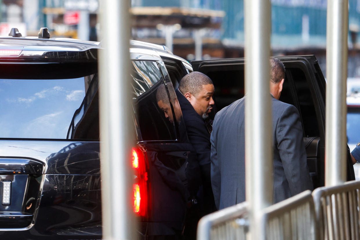 Manhattan District Attorney Alvin Bragg gets out of a shiny black vehicle, beside some barricades.