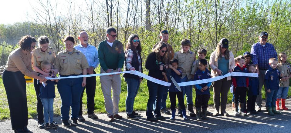 Holmes County Park District board member Irene Burgett cuts the ribbon to celebrate the completion of the H2Ohio project at Killbuck Creek and Sand Run Wetland, as other board members Ashley Vaughn and Dan Mathie, Park District Director Jen Halverson, several Holmes County Scouts, ODNR's John Navarro and Karen Gotter and Trevor Berger of Soil ad Water Conservation District look on.