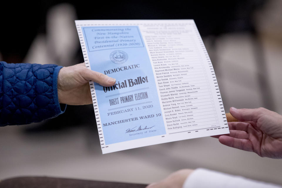 FILE - A woman takes a Democratic ballot to vote in the New Hampshire Primary at Parker-Varney Elementary School, Feb. 11, 2020, in Manchester, N.H. The Democratic National Committee’s rulemaking arm voted on a revamped schedule for early votes for the 2024 presidential primary: first South Carolina, followed by New Hampshire and Nevada on the same day, then Georgia and finally Michigan. (AP Photo/Andrew Harnik, File)