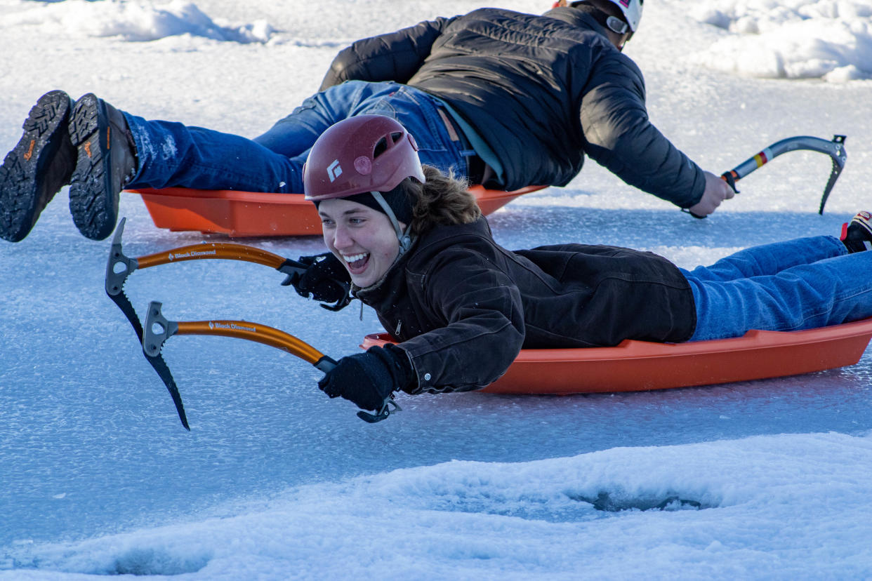 Wisconsin Union Winter Carnival attendees participate in horizontal ice climbing/ice pick sledding.