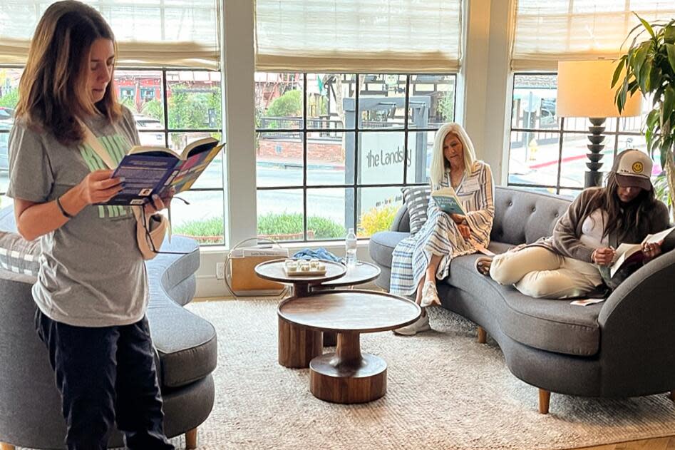 Women reading books in a hotel lobby with large paned windows