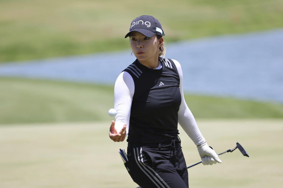 Hinako Shibuno, of Japan, tosses the ball to her caddie on the ninth green during the first round of the LPGA golf tournament Wednesday, April 12, 2023, near Honolulu. (AP Photo/Marco Garcia)