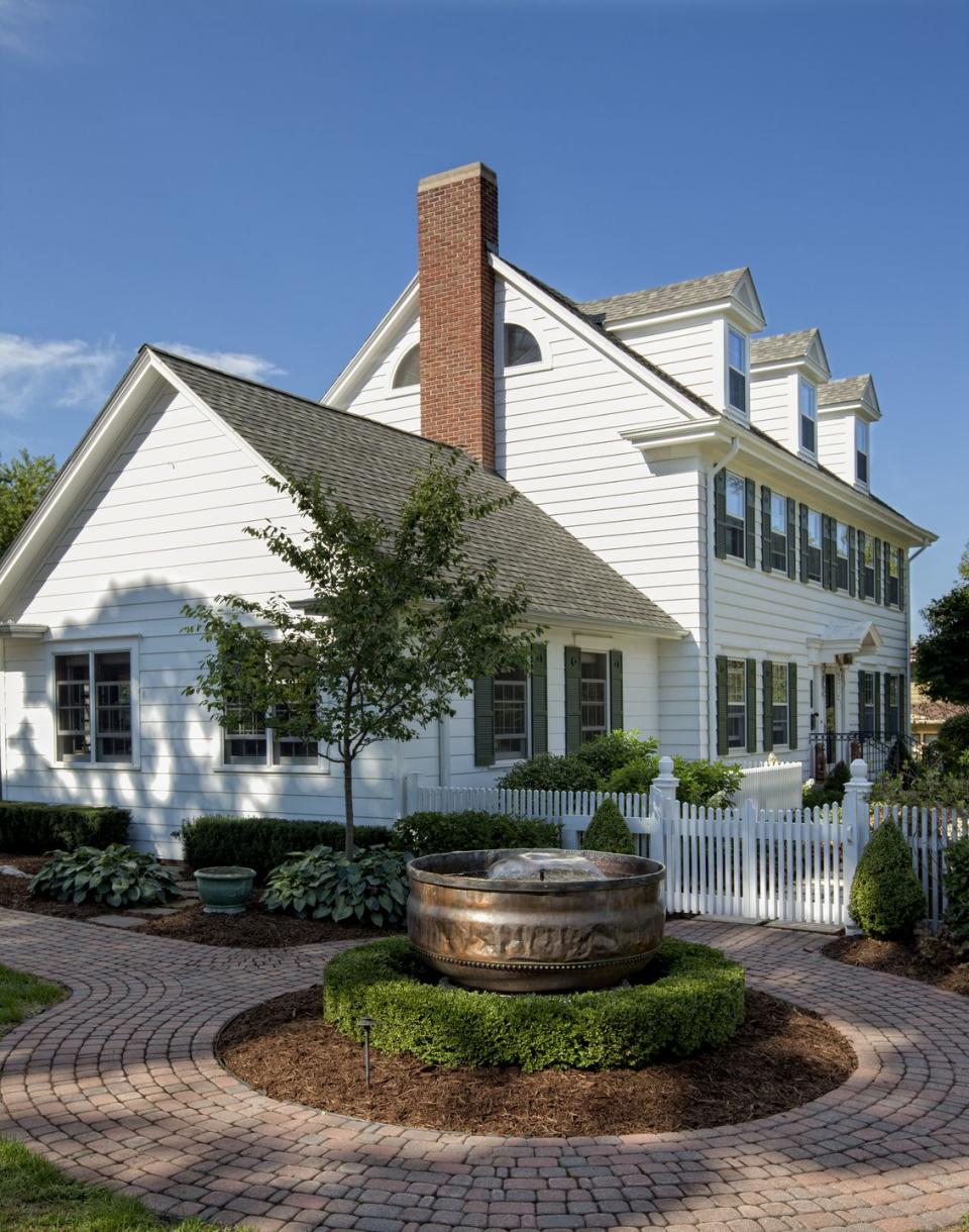 White, colonial style house with landscaping on a clear day