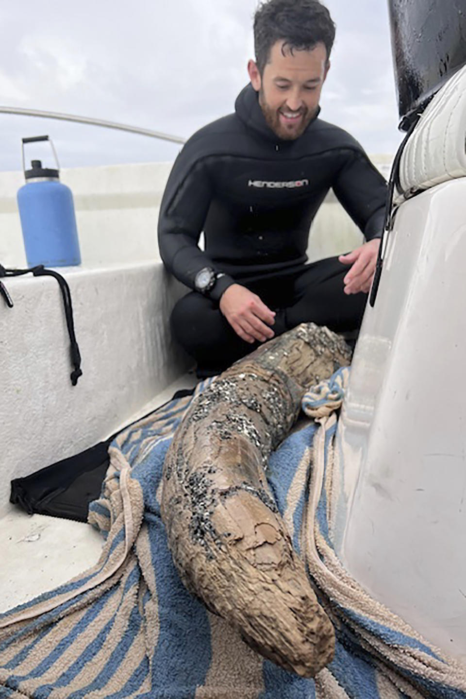 This April 2024 photo taken by Blair Morrow and provided by Alex Lundberg shows Lundberg with a large section of tusk from a long-extinct mastodon that he and his diver companion found on the sea floor off Florida's Gulf coast. They first thought it was just a large piece of wood. (Blair Morrow via AP)