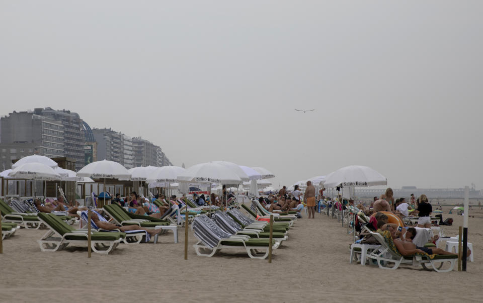 People lay on chairs at the Belgian seaside resort of Blankenberge, Belgium, Tuesday, Aug. 11, 2020. A skirmish took place on the beach on Saturday, Aug. 8, 2020 which resulted in two coastal communities banning day trippers from the city. (AP Photo/Virginia Mayo)