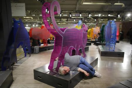 A participant rests under an animal figure at the World Climate Change Conference 2015 (COP21) at Le Bourget, near Paris, France, December 12, 2015. REUTERS/Stephane Mahe