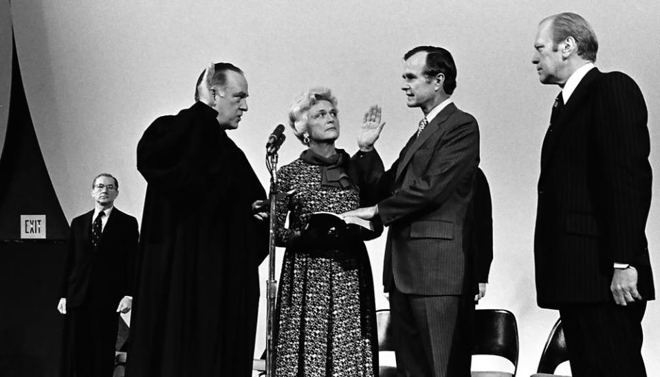 President Gerald R. Ford and Barbara Bush watch as Justice Potter Stewart swears in George H.W. Bush as the new Director of the CIA, at CIA HQ in Langley, Virginia on Jan. 26, 1976. The outgoing Director William Colby is at the left in the background.