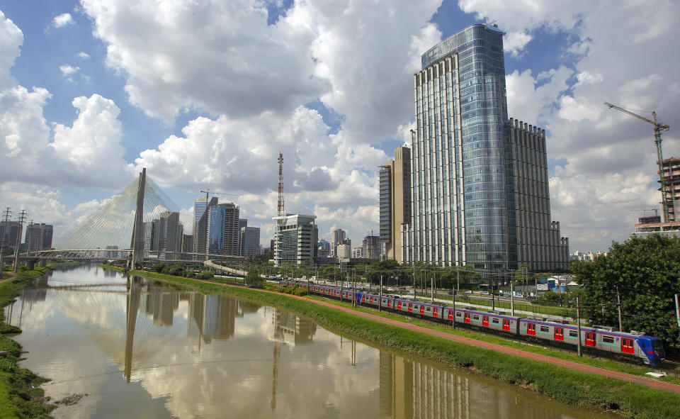 Office buildings are seen as a commuter train rides along the shore of the Pinheiros River in Sao Paulo, Brazil, Wednesday, March 14, 2012. A just-released report prepared by American consulting firm KPMG and France's Greater Paris Investment Agency shows that Sao Paulo now beats out New York as the top destination for foreign investments in the Americas. (AP Photo/Andre Penner)