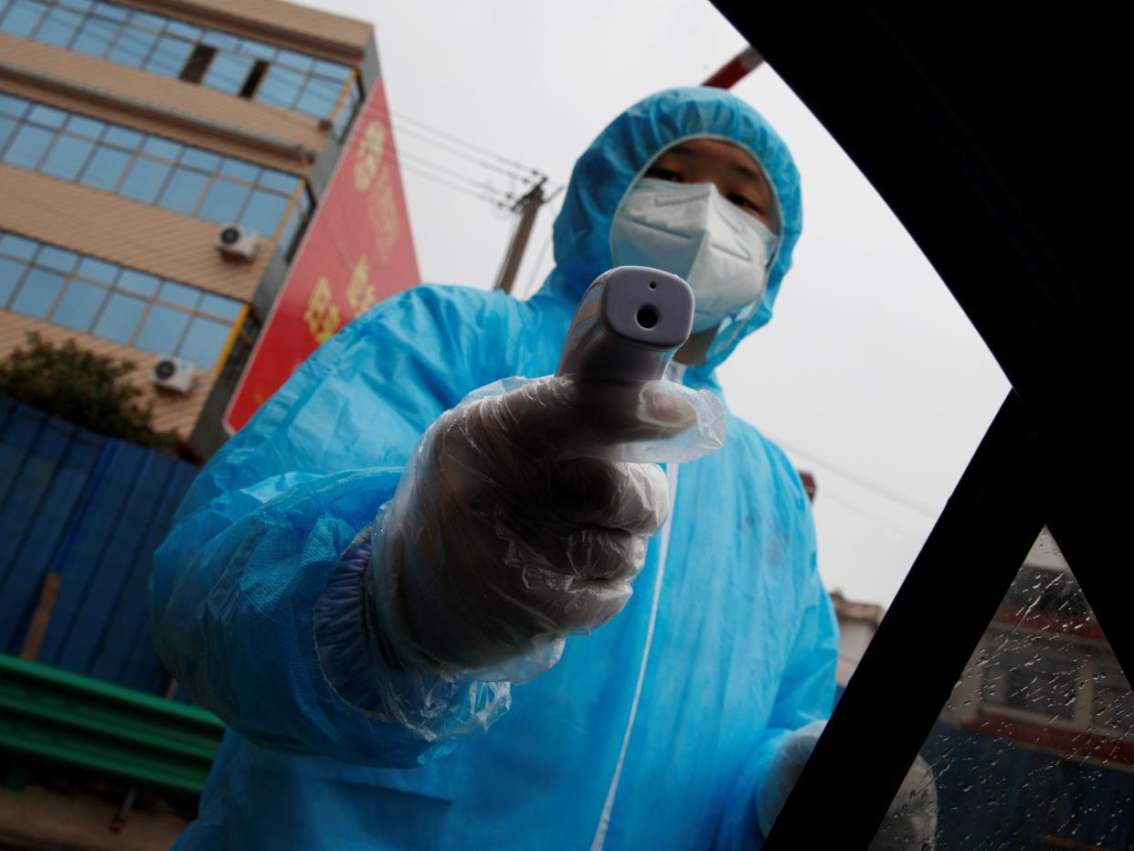 A medical worker holds a thermometer to check a passenger's temperature at a checkpoint as the country is hit by an outbreak of the novel coronavirus in Susong County, Anhui province, China, February 6, 2020. REUTERS/Thomas Peter