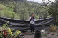 Jeimmer Alejandro Riveros, 9, takes photos with a friend's camera on his mother's small farm in Chipaque, Colombia, Saturday, May 9, 2020. Alejandro, his mother and his older brother are reinventing themselves as YouTubers due to a quarantine ordered by the government to contain the spread of COVID-19, teaching others how to grow vegetables at home and providing self-starter kits that they deliver through a local courier. (AP Photo/Fernando Vergara)