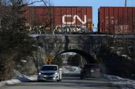 Car passes through a tunnel under a Canadian National Railway (CN Rail) train, halted near a Tyendinaga Mohawk Territory camp