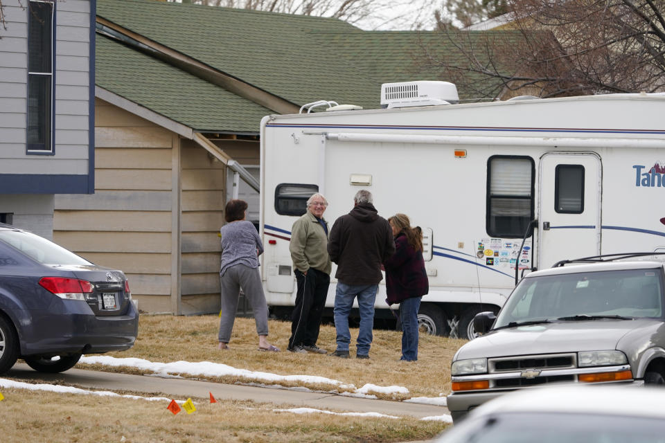 Neighbors gather on the lawn next to the home of Kirby Klements after a piece of debris crushed the man's pickup truck parked next to his home in Broomfield, Colo., as a passenger plane shed parts while making an emergency landing at nearby Denver International Airport Saturday, Feb. 20, 2021. (AP Photo/David Zalubowski)