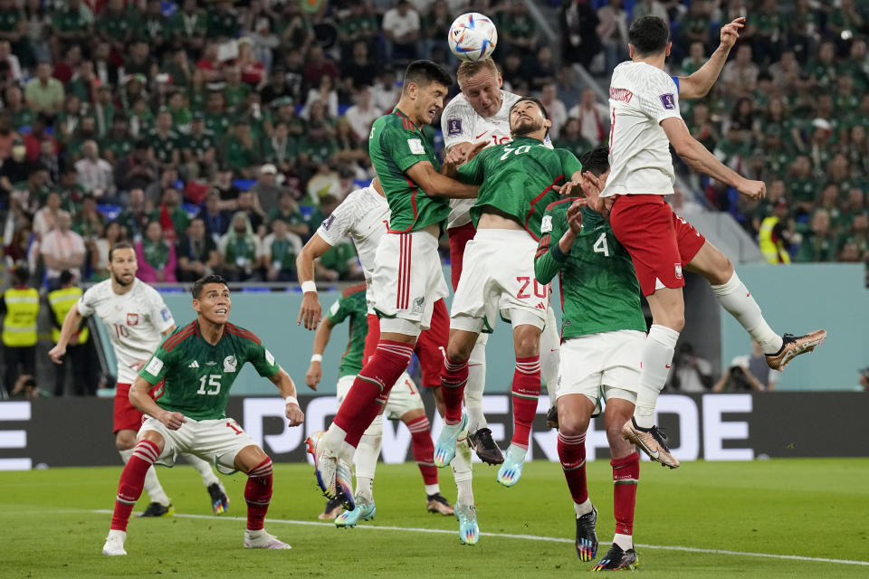 Poland's Kamil Glik and Mexico's Henry Martin (20) go for a header during a World Cup group C soccer match at the Stadium 974 in Doha, Qatar, Tuesday, Nov. 22, 2022. (AP Photo/Martin Meissner)