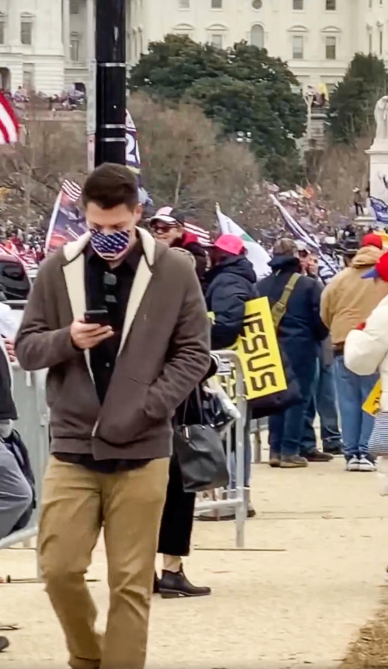 Zach Henry looks at his phone while walking through a crowd at the Capitol on January 6, 2021 (via Facebook)