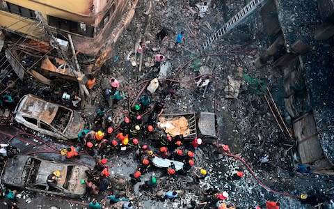 Rescue personnel carry the body of a victim after a fire broke out in Dhaka  - Credit: AFP