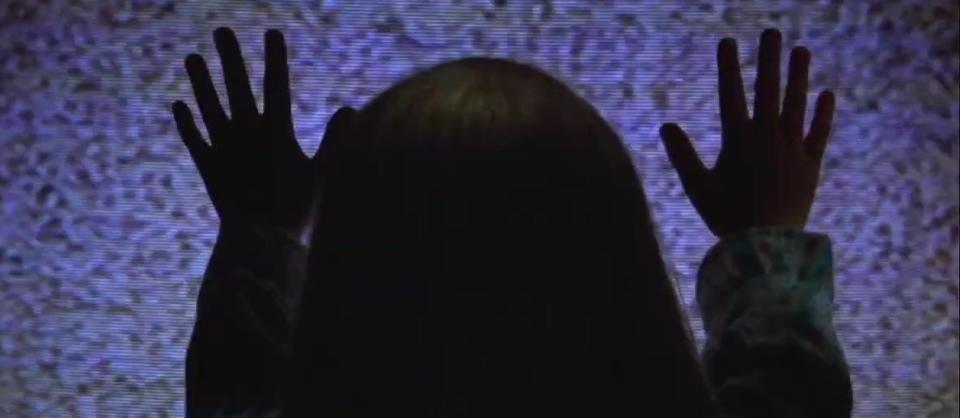 Carol Anne putting her hands on a TV screen in "Poltergeist"