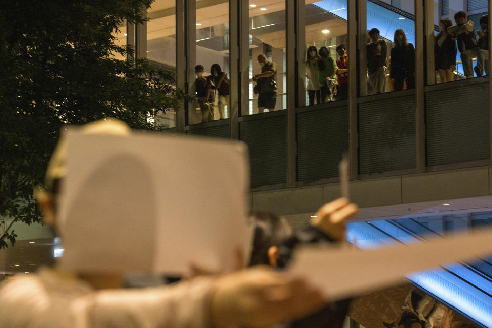 People watch from above at a protest gathering at the University of Hong Kong in Hong Kong, Tuesday, Nov. 29, 2022. On Tuesday, about a dozen people gathered at the University of Hong Kong, chanting against virus restrictions and holding up sheets of paper with critical slogans. Most were from the mainland, which has a separate legal system from the Chinese territory of Hong Kong, and some spectators joined in their chants. (AP Photo/Bertha Wang)