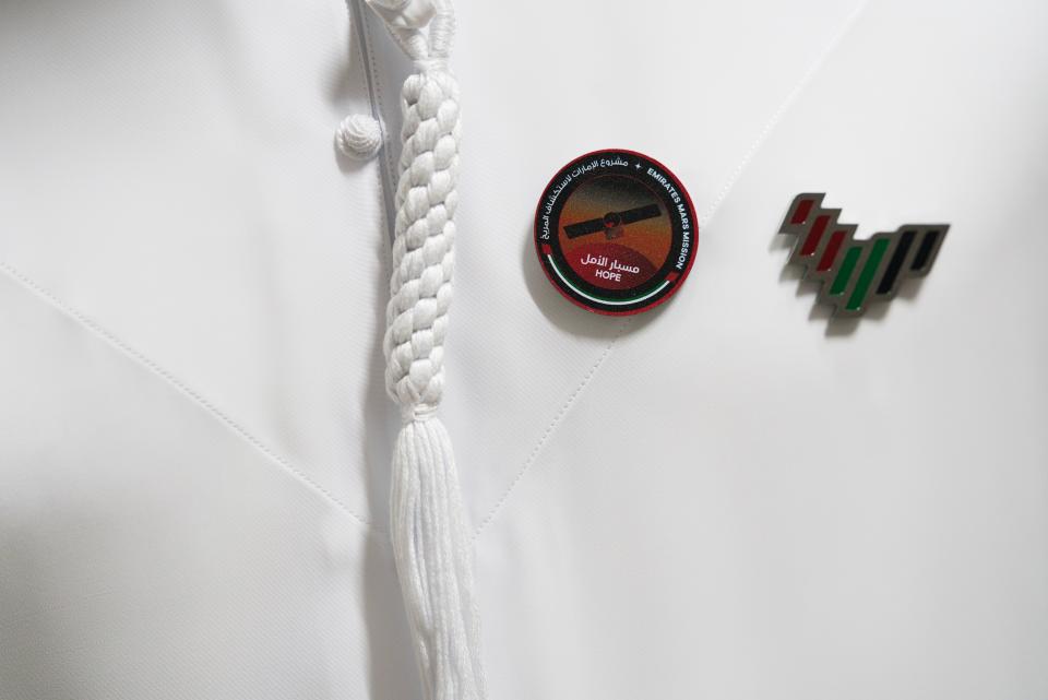 An Emirati scientist wears pins symbolizing the Emirates' Hope space probe to Mars and the United Arab Emirates at the Mohammed bin Rashid Space Centre in Dubai, United Arab Emirates, Sunday, July 19, 2020. A Japanese H-IIA rocket carrying a United Arab Emirates Mars spacecraft has been placed on the launch pad for Monday's scheduled liftoff for the Arab world's first interplanetary mission, officials said Sunday. (AP Photo/Jon Gambrell)