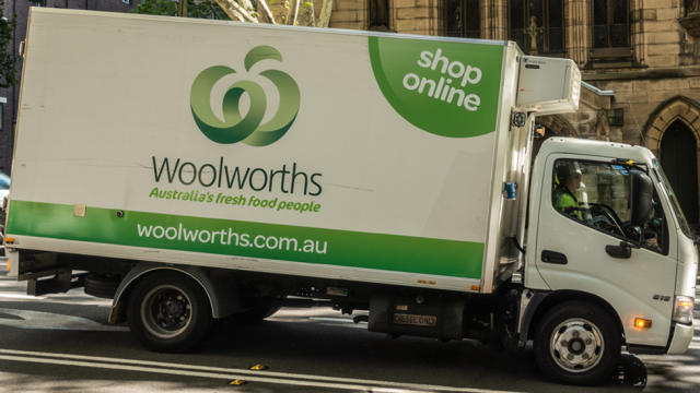Pictured is a Woolworths delivery truck stopped in a street. 
