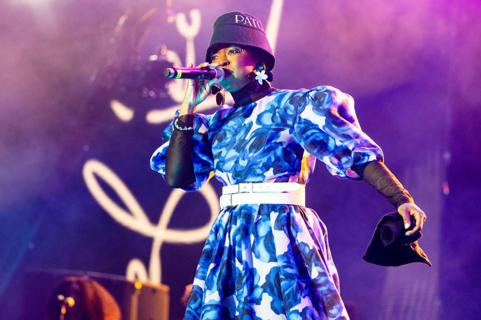 Lauryn Hill in a blue floral dress, white belt, and black bucket hat