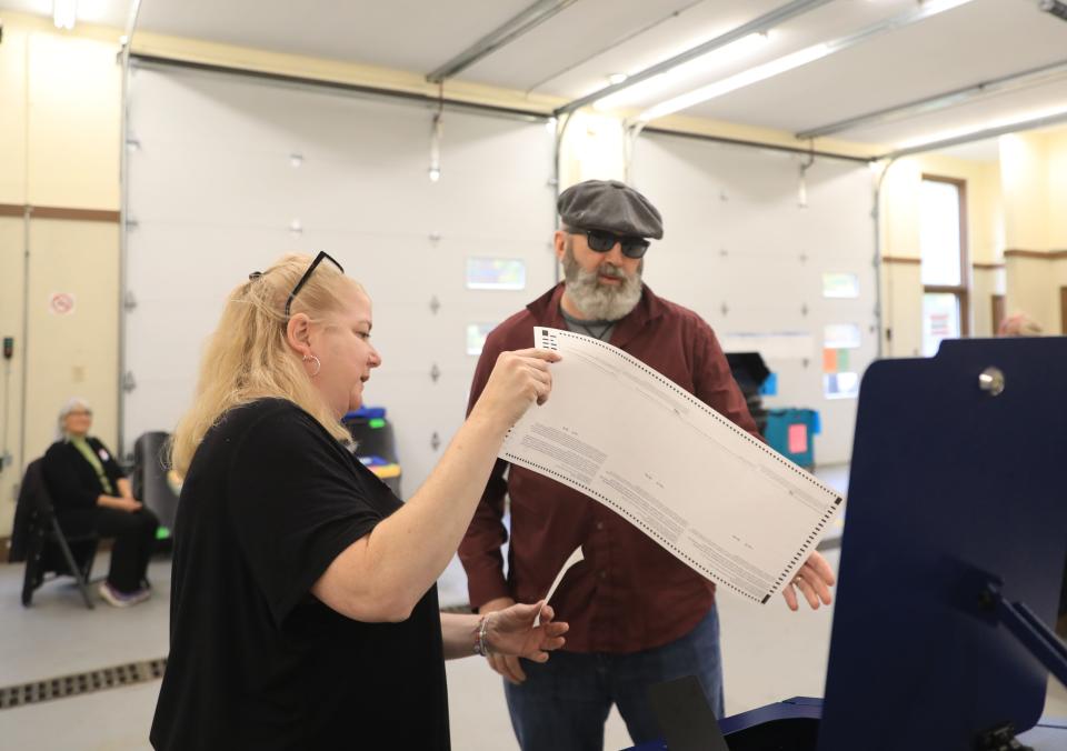 Poll worker, Victoria Savery hands a ballot to Terrence Mills at the New Hamburg Fire District in the Town of Poughkeepsie on November 7, 2023.