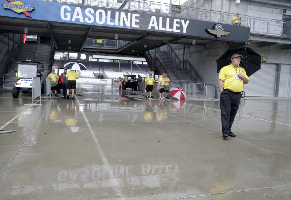 Security personnel attempt to shield themselves from the rain that halted NASCAR Xfinity Series auto racing practice at the Indianapolis Motor Speedway in Indianapolis, Friday, Sept. 7, 2018. (AP Photo/Michael Conroy)