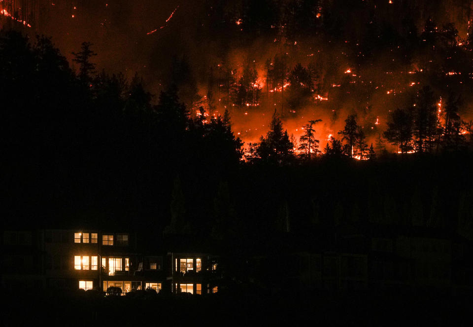 The McDougall Creek wildfire burns on the mountainside above a home in West Kelowna, B.C., on Friday, August 18, 2023. THE CANADIAN PRESS/Darryl Dyck