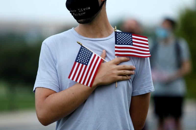 Activists stand with American flags at sunrise to memorialize victims of the coronavirus disease (COVID-19) outbreak in Washington