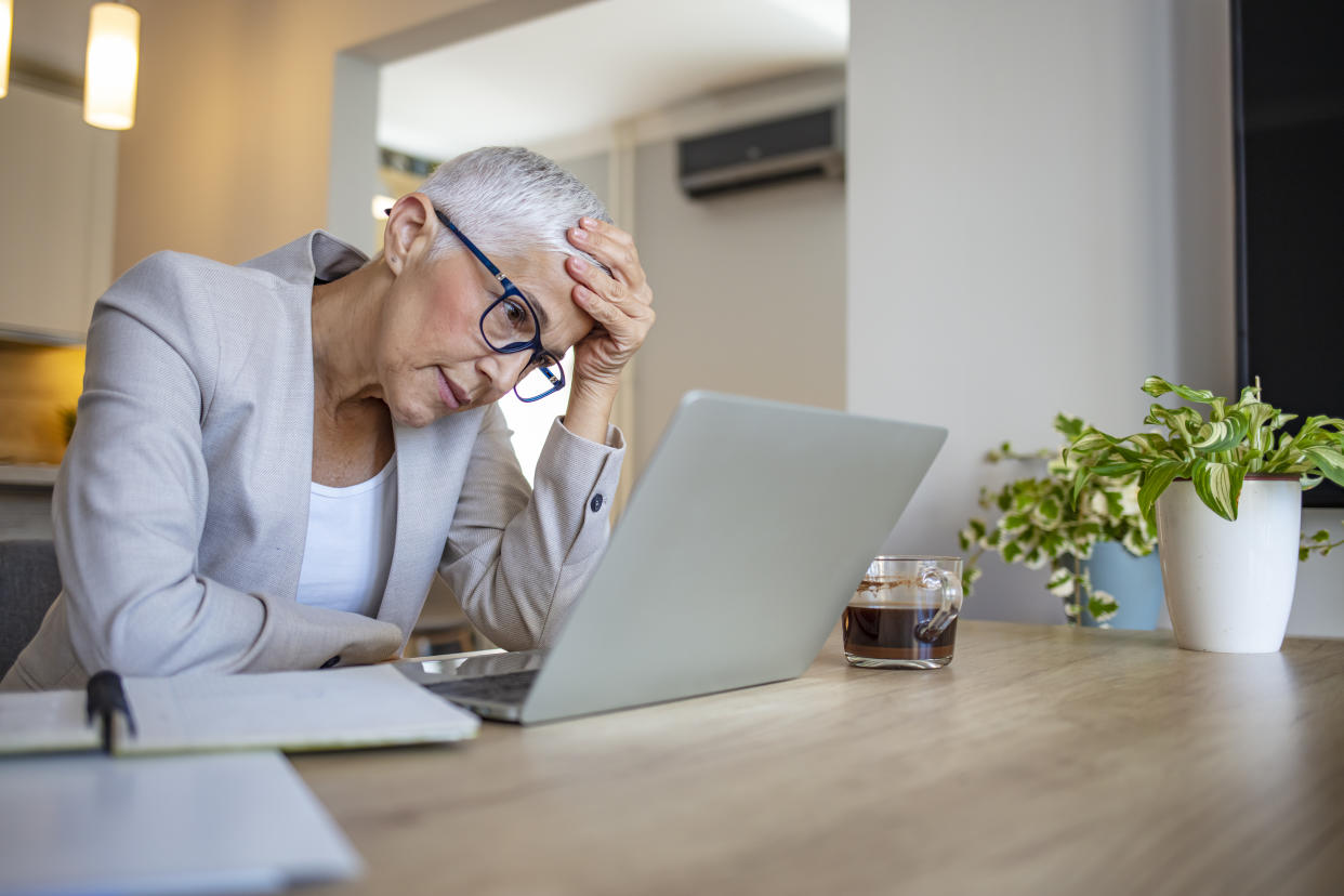 Old exhausted business woman feeling very tired. Senior tired business woman overworking in front of laptop, touching her eyes, free space. Struggling to find a solution