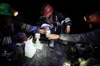 Artisanal gold miners drink anise and chew coca leaves as part of a ritual before starting work in a mine in La Rinconada, in the Andes