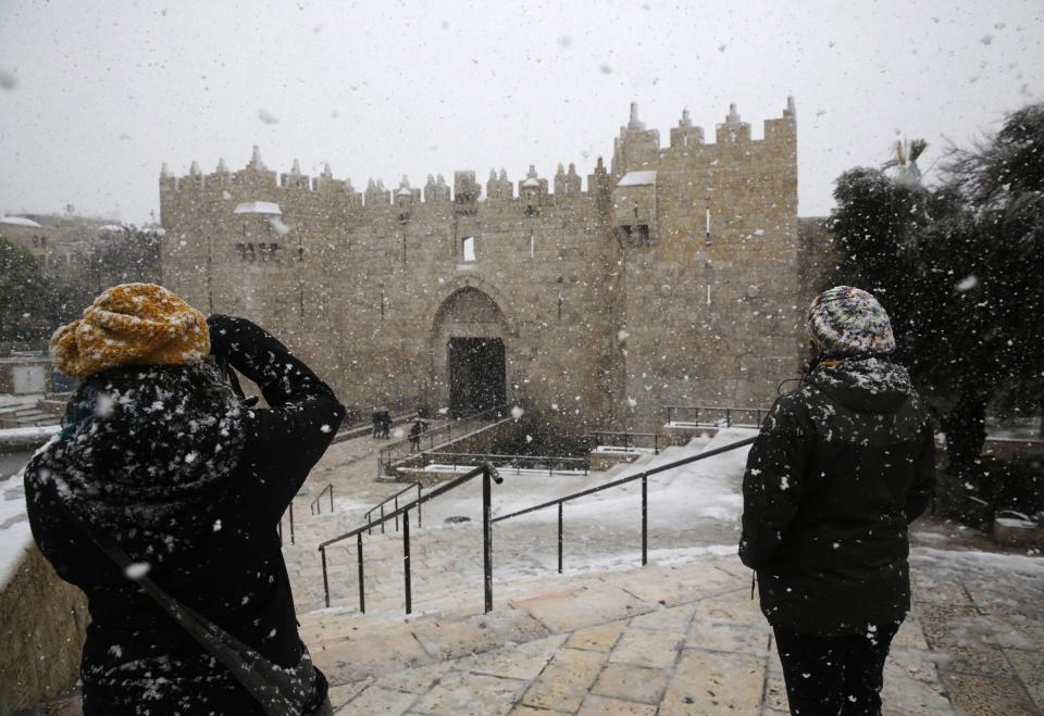 A woman takes pictures during snowfall in winter near Damascus Gate outside Jerusalem's Old City