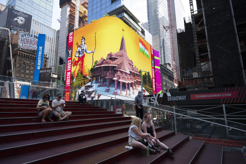 People take a break in Times Square as the imagery of the Hindu deity Ram and 3-D portraits of the proposed Hindu temple are displayed on a digital billboard, New York, Wednesday, Aug. 5, 2020, to celebrate the groundbreaking ceremony of a temple dedicated to the Hindu god Ram by Indian Prime Minister Narendra Modi in Ayodhya, in New Delhi, India. Hindus rejoiced as Modi broke ground on a long-awaited temple of their most revered god, Ram, at the site of a demolished 16th century mosque. (AP Photo/Mark Lennihan)