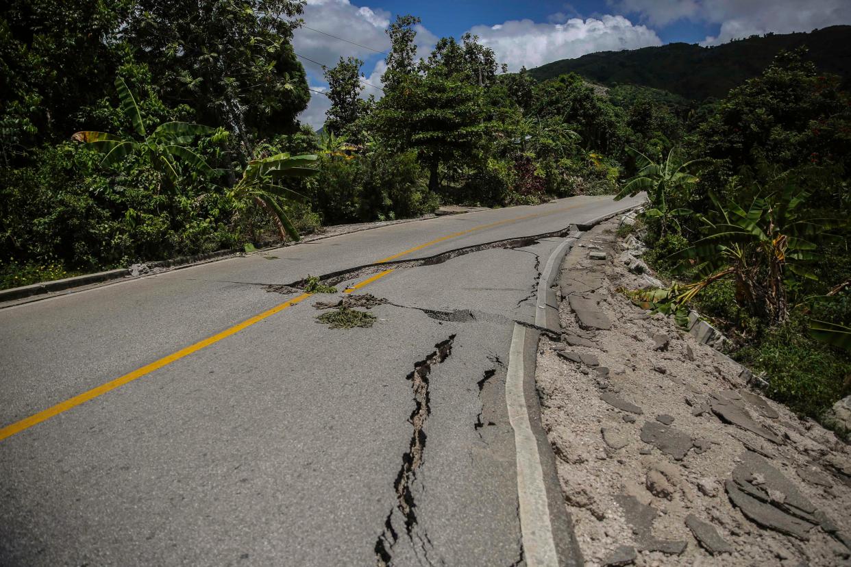 A road is damaged by the earthquake in Camp-Perrin, Les Cayes, Haiti, Sunday, Aug. 15, 2021. The death toll from the magnitude 7.2 earthquake in Haiti soared on Sunday as rescuers raced to find survivors amid the rubble ahead of a potential deluge from an approaching tropical storm.