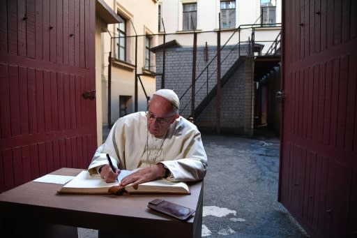 Pope Francis writes in the guestbook of a museum in the former KGB building in Vilnius where Soviet regime opponents were tortured and killed