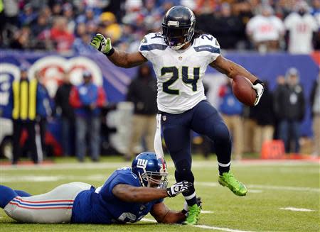 Dec 15, 2013; East Rutherford, NJ, USA; Seattle Seahawks running back Marshawn Lynch (24) breaks the tackle of New York Giants defensive tackle Cullen Jenkins (99) during the second half at MetLife Stadium. Mandatory Credit: Joe Camporeale-USA TODAY Sports