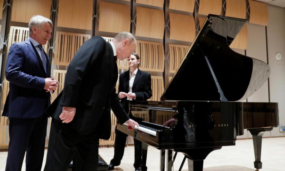 Vladimir Putin, centre, touches a piano key, as Novatek’s CEO Leonid Mikhelson, left, looks on during the president’s visit.