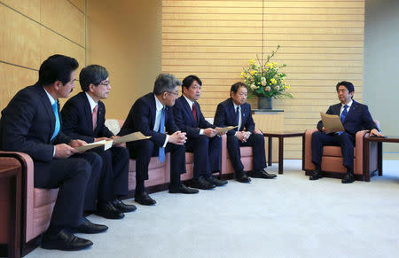 Japanese Prime Minister Shinzo Abe (R) speaks to Hiroshi Imazu, (2nd R), Chairman of Research Commission on Security of Japan's ruling Liberal Democratic Party (LDP), and other LDP representatives after a proposal on missile defense was submitted to Abe at the prime minister's office in Tokyo, March 30, 2017. REUTERS/Eugene Hoshiko/Pool