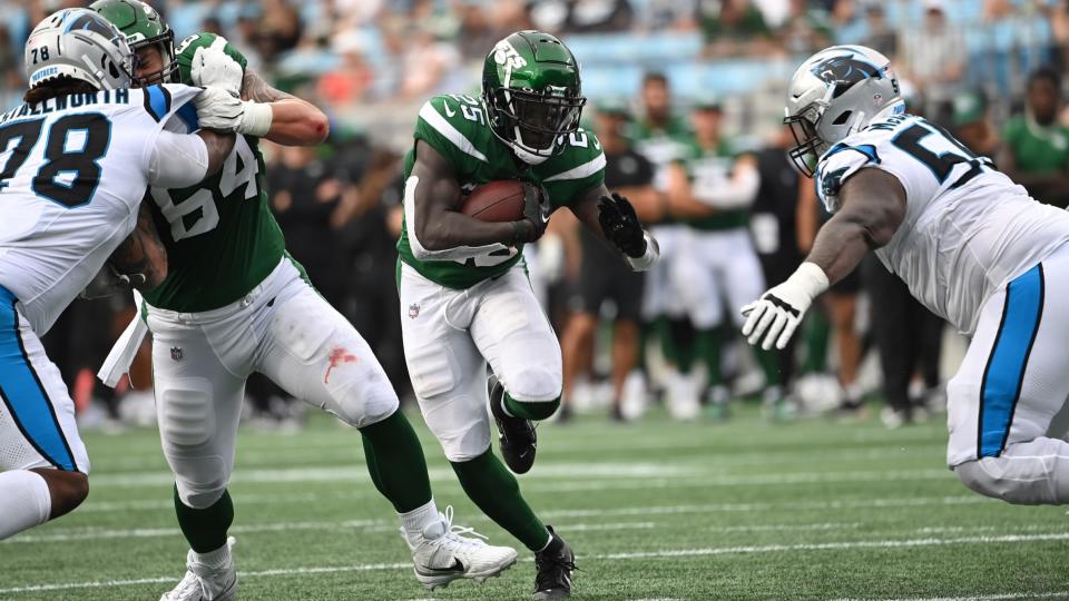 12 de agosto de 2023;  Charlotte, Carolina del Norte, Estados Unidos;  New York Jets corriendo hacia atrás Israel Abanikanda (25) con el balón mientras los tackles defensivos de Carolina Panthers Taylor Stallworth (78) y Marquan McCall (55) defienden en el último cuarto en el estadio Bank of America