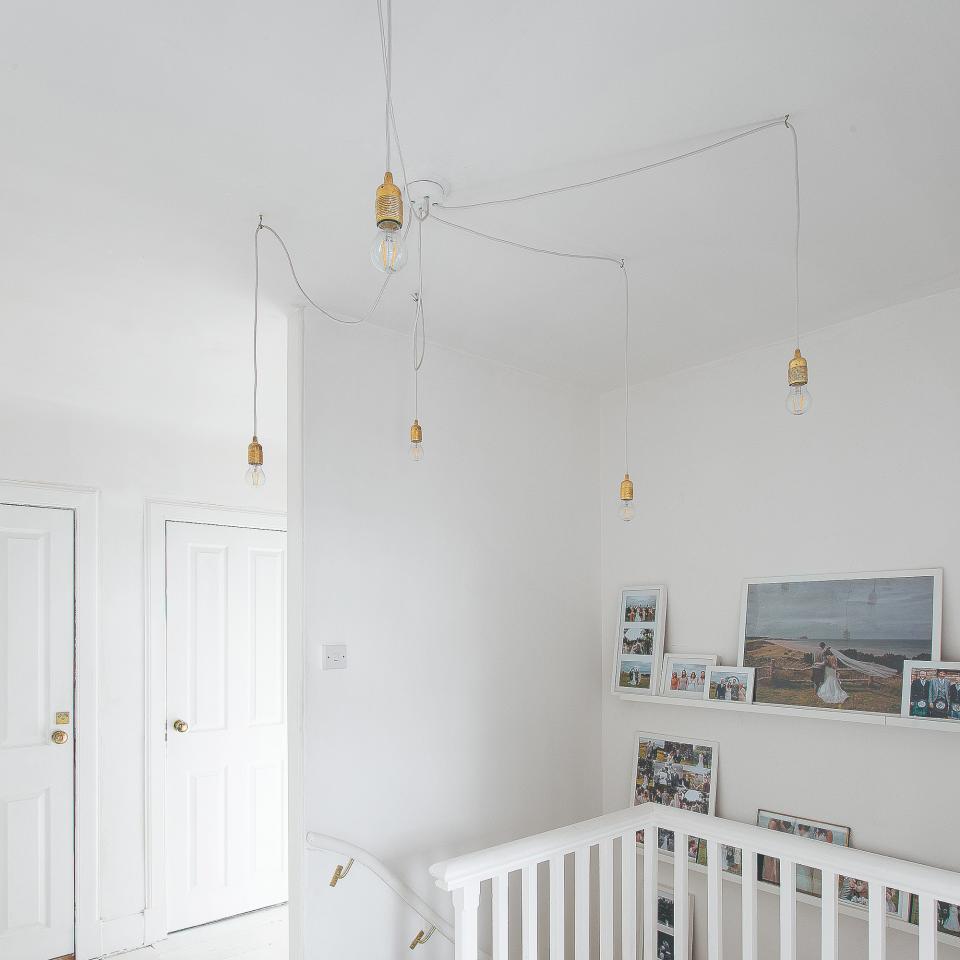 White-painted hallway and staircase with pendant lights and photos on the wall