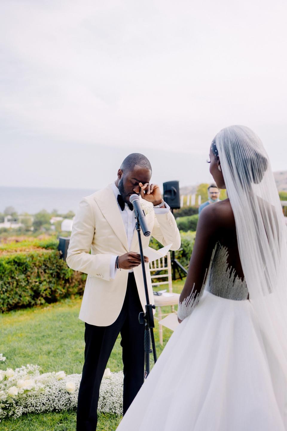 A groom wipes a tear away as he says his vows to his bride.