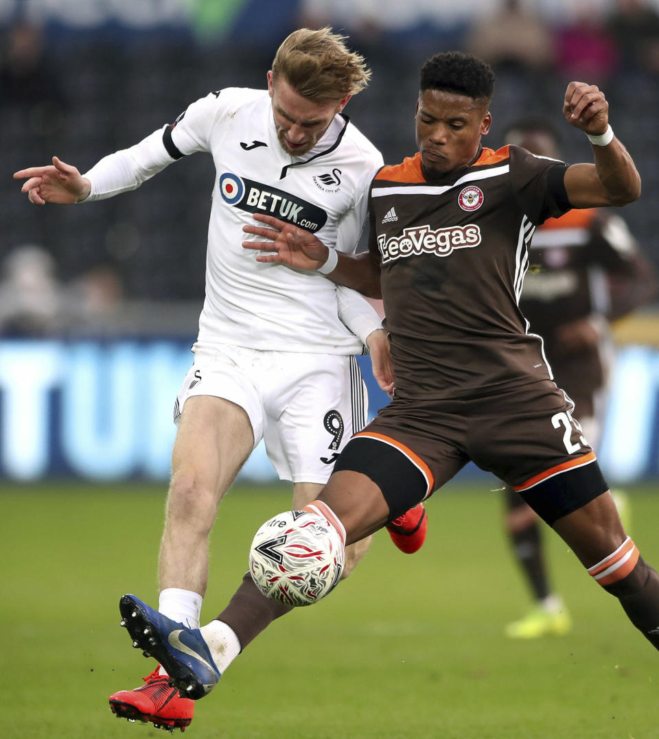 Swansea City's Oliver McBurnie, left, and Brentford's Julian Jeanvier during their English FA Cup fifth round soccer match at the Liberty Stadium in Swansea, England, Sunday Feb. 17, 2019. (Nick Potts/PA via AP)