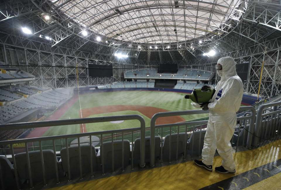 A worker wearing protective gears disinfects as a precaution against the new coronavirus at Gocheok Sky Dome in Seoul, South Korea, Tuesday, March 17, 2020. The Korea Baseball Organization has postponed the start of new season to prevent the spread of the new coronavirus. For most people, the new coronavirus causes only mild or moderate symptoms. For some it can cause more severe illness. (AP Photo/Lee Jin-man)