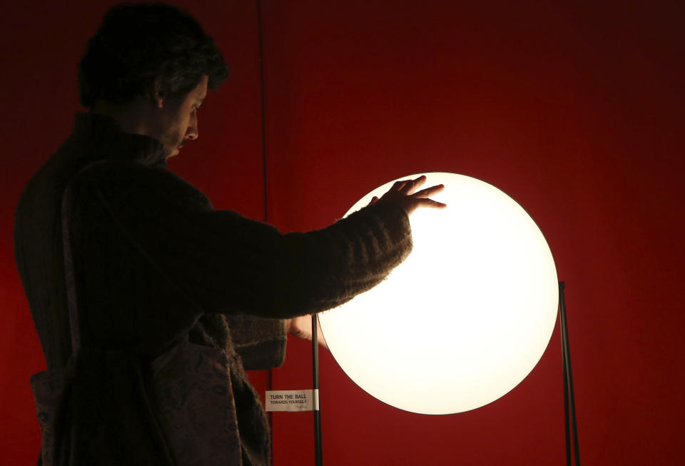 A man touches a lamp called "Light Sister" on display at the Milan Design Fair, in Milan, Italy, Thursday, April 11, 2013. The Milan furniture and design week fair, showcasing the latest in furniture and design from countries around the world, will continue until Sunday. (AP Photo/Antonio Calanni)