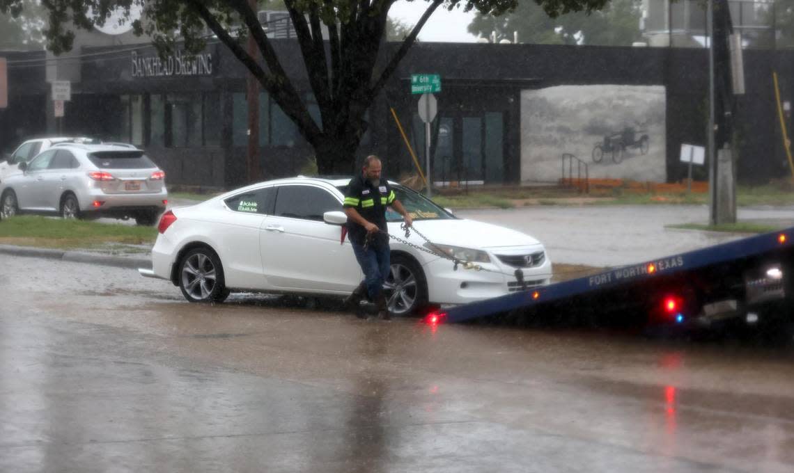 A tow truck operator hooks up a vehicle stranded by flash flooding on University Drive near the intersection with West 7th Street on Monday, August 22, 2022.