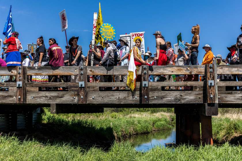 TOPSHOT - Climate activist and Indigenous community members gather on top of the bridge after taking part in a traditional water ceremony during a rally and march to protest the construction of Enbridge Line 3 pipeline in Solvay, Minnesota on June 7, 2021. - Line 3 is an oil sands pipeline which runs from Hardisty, Alberta, Canada to Superior, Wisconsin in the United States. In 2014, a new route for the Line 3 pipeline was proposed to allow an increased volume of oil to be transported daily. While that project has been approved in Canada, Wisconsin, and North Dakota, it has sparked continued resistance from climate justice groups and Native American communities in Minnesota. While many people are concerned about potential oil spills along Line 3, some Native American communities in Minnesota have opposed the project on the basis of treaty rights and calling President Biden to revoke the permits and halt construction. (Photo by Kerem Yucel / AFP) (Photo by KEREM YUCEL/AFP via Getty Images)