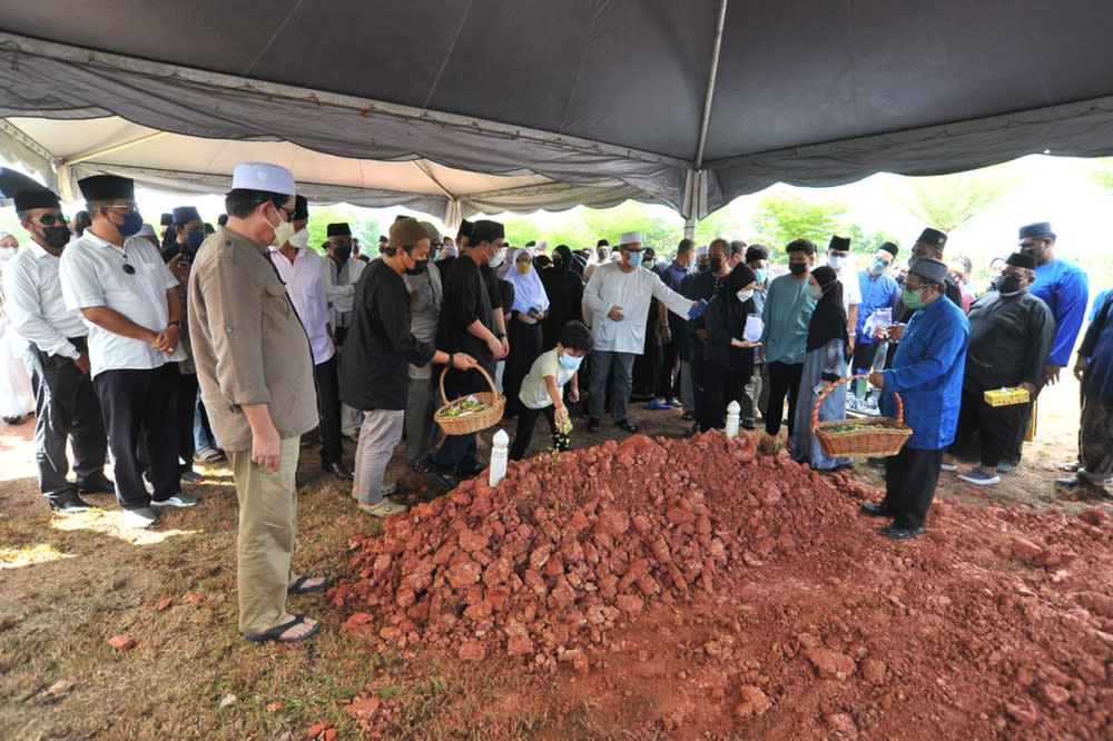 Close family members and friends of former Johor mentri besar Datuk Osman Sapian sprinkling rose water after his remains were laid to rest at the Ar Raudhah Islamic Cemetery in Mount Austin, Johor Baru. December 22, 2021. — Picture by Ben Tan